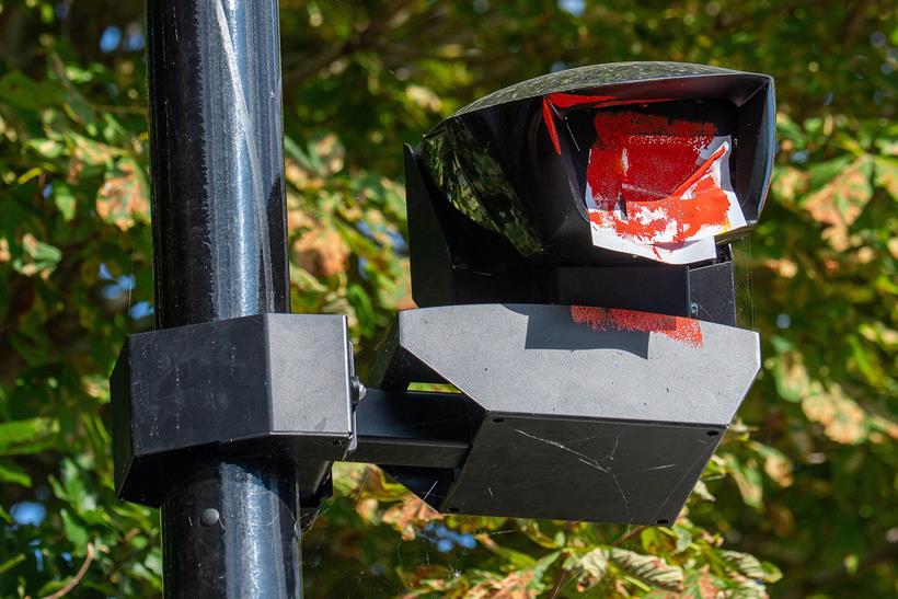 A ULEZ camera vandalised with paint and a sticker