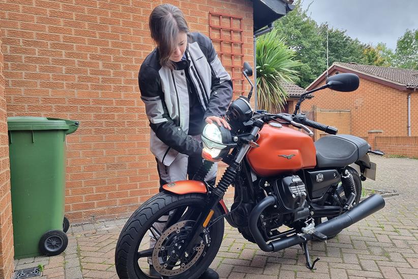 Saffron attends to the headlight on the Moto Guzzi V7